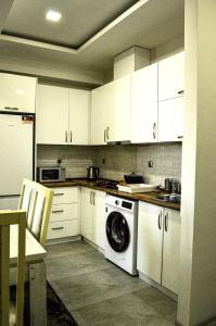 Una cocina con gabinetes blancos y lavadora. en X2 Development Luxury Apartment with Terrace & Panoramic View, en Tiflis