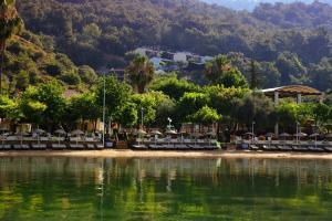 a beach with chairs and trees next to the water at Hotel Meri All inclusive in Oludeniz