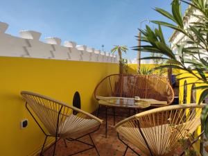 a patio with chairs and tables and a yellow wall at Riad Kech Soul Boutique & Spa in Marrakech
