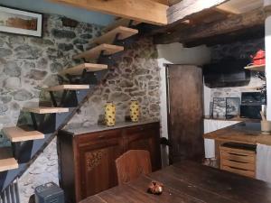 a kitchen with a stone wall and a wooden table at Aile de la Maison de Chouliou in Balaguères