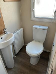 Un baño con un inodoro blanco y un lavabo. en Beech Rise, Primrose Valley, Filey, en Filey