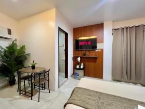 a bedroom with a bed and a table and a tv at Casa Marga Inn, Panglao in Panglao Island