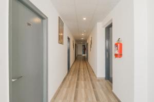 um corredor com paredes brancas e piso de madeira em Hotel O Perky Stay em Faridabad