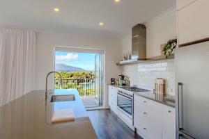 a kitchen with a sink and a stove top oven at Boat Shed Bay - Stunning Lake Tarawera Views in Rotorua +43 photos