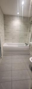 a bathroom with a bath tub and a toilet at Next to Southall Station - Brand new Apartment Room in Southall +4 photos