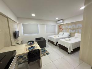 a hotel room with two beds and a table at Estúdios Time in Maceió