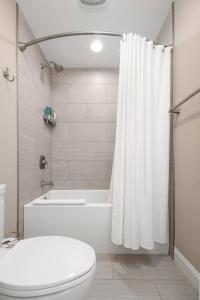 a bathroom with a toilet and a tub and a shower curtain at James Island 2br Eco-haven Beachgolfdowntown! in Charleston +14 photos