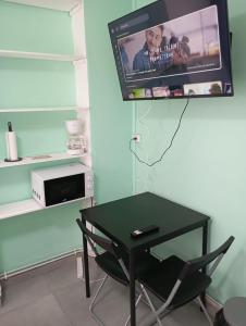 ein Raum mit einem Tisch und einem Fernseher an der Wand in der Unterkunft Studio rénové proche métro in Lille