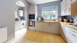 a large kitchen with white cabinets and a window at Harmony Retreat in Cardiff