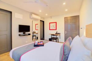 una camera da letto con un grande letto bianco e una televisione di Townhouse Alpha a Pune