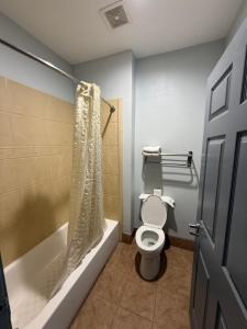 a bathroom with a toilet and a bathtub with a shower curtain at Budget Host Inn Stafford - Houston in Houston