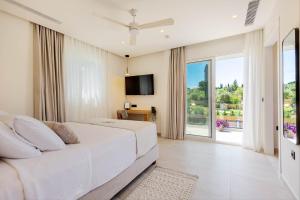a bedroom with a white bed and a large window at Luxury Villa Rika Corfu- 5 bedrooms with Pool in Gouvia