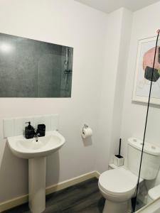 een witte badkamer met een toilet en een wastafel bij Hotel Feel, Home Comfort in Manchester