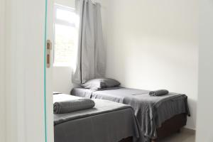 a bedroom with two beds and a window at Apto completo e bem localizado em araucária in Araucária
