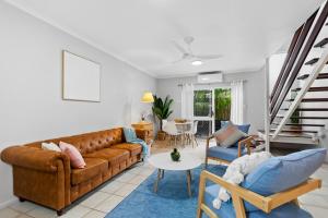 un soggiorno con divano marrone e sedie di Tide and Seek at Trinity Beach a Trinity Beach