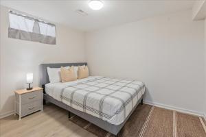 a white bedroom with a bed and a night stand at Stewarts Place Newly Renovated Basement City Apartment in Hamilton