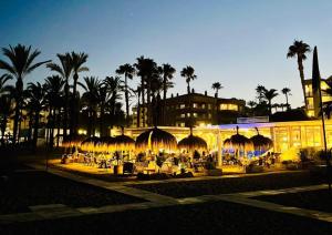 un edificio illuminato con sedie e palme di notte di La Nogalera Experience a Torremolinos