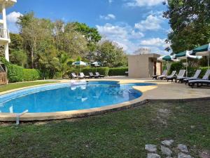 a swimming pool with chairs and umbrellas in a yard at Villas Chicanna Calakmul in Chicanna