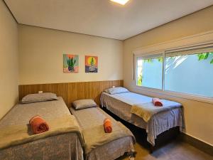 a bedroom with two beds and a window at Brisas de Bonito: ótima casa, condomínio, 2 suítes in Bonito +30 photos