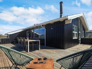 a house with a wooden deck with a table and chairs at 6 person holiday home in Hjørring in Hjørring