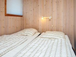a bedroom with two beds in a wooden wall at 4 person holiday home in Fanø-By Traum in Fanø