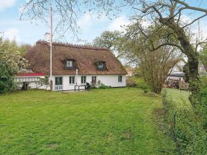 a house with a thatched roof and a grass yard at 6 person holiday home-By Traum in Augustenborg
