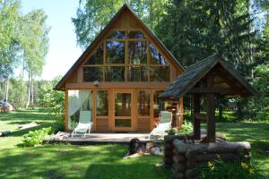 a cabin with a dog laying in the grass at Holiday Home Bērzlejas in Upesgrīva