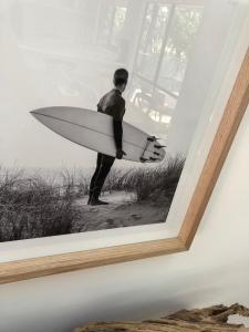 a picture of a man holding a surfboard on a wall at Beachside Phillip Island in Cowes