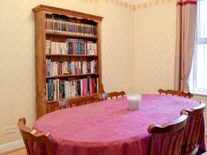 a room with a table with a book shelf filled with books at Middleton House in Filey