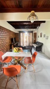 ein Wohnzimmer mit einem Tisch und orangefarbenen Stühlen in der Unterkunft Condomínio Village do Araripe - Casa Brisa da Serra in Gravatá