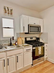 a kitchen with white cabinets and a stove and a microwave at Spacious 3BR Apartment - 12min Newark Airport -Near NYC & Malls in Newark