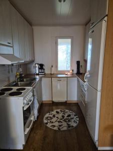 a kitchen with white appliances and a wooden floor at Small cottage in Toholampi