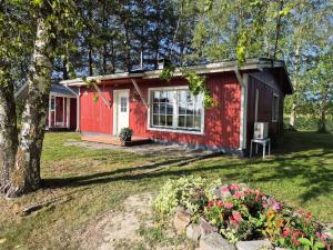 a red tiny house in a yard with flowers at Small cottage in Toholampi