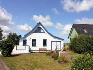 a white house with a blue roof on a yard at Wunderschönes Ferienhaus am Schilfufer in Barth in Barth