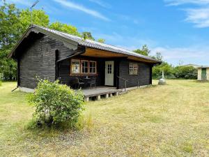 Una pequeña casa negra con un porche en un campo. en 5 person holiday home in BORGHOLM, en Borgholm