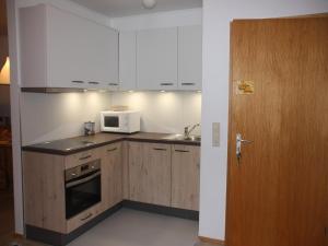une cuisine avec des placards blancs et un four micro-ondes ainsi qu'une porte dans l'établissement Cozy Holiday Apartment on Fehmarn, à Petersdorf auf Fehmarn