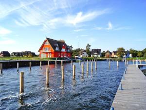 a red house on the water with a dock at Haus in Vieregge am Breetzer Bodden in Vieregge