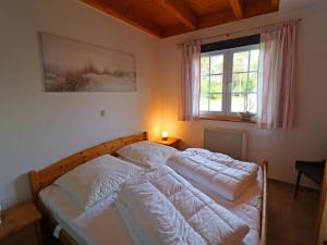 a bedroom with a bed with white sheets and a window at Doppelhaushälfte Bernsteinhaus II, Trassenheide in Trassenheide
