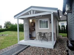 a white shed with a table and chairs at Dziwnówek Holiday House near Beach in Dziwnówek