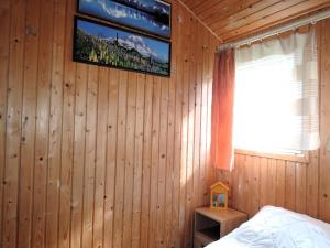 a bedroom with a wooden wall with a window and a bed at Bungalow near the Baltic Sea Beach in Wrzosowo