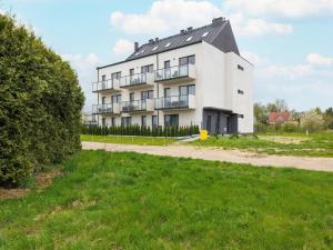 レバルにあるHoliday Apartment Rewal Baltic Beachの野原に建つバルコニー付きの大きな白い建物