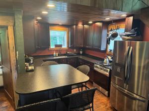 a kitchen with a table and a stainless steel refrigerator at Boulderwoods Cabin in Speedwell