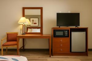 a room with a television on a dresser with a desk at Sunset Inn - Augusta in Augusta