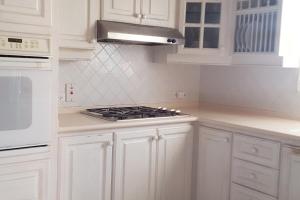 a kitchen with white cabinets and a stove top oven at Tranquility in Saint James +12 photos