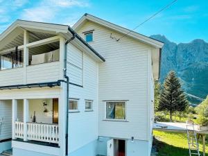 a white house with a balcony and mountains in the background at 4 person holiday home in LAUPSTAD in Laupstad