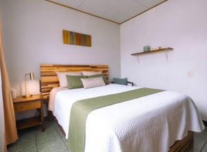 a bedroom with a large bed and a table with a lamp at Hojas Verdes Rental House Excelente ubicación cerca de Campo Ferial Palmares in Palmares