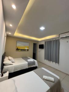 a hotel room with two beds and a tv at Suítes Nativa in Trairi