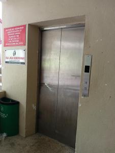 a metal elevator door in a building with a trash can at seaview beach homestay pd ground floor in Port Dickson +13 photos