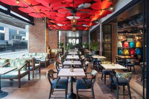 バンコクにあるメルキュール バンコク スクンビットのテーブルと椅子、赤い傘が備わるレストラン