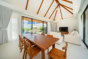 Un comedor con mesa y sillas de madera. en Anchan Villas Phuket - 4 BR Signature Pool Villa by Escape Villas, en Ban Phru Champa